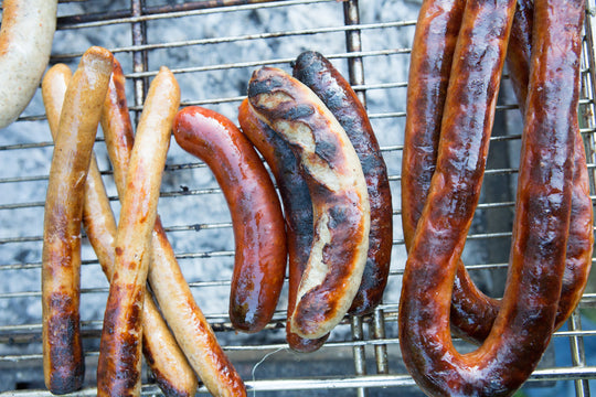 frank furters, bratwursts, and kielbasa on a grill