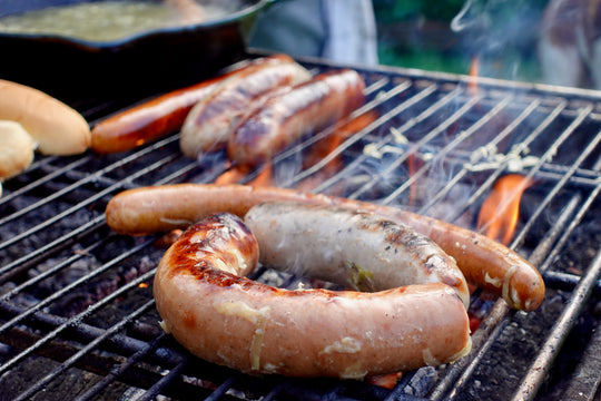 a charcoal grill with hotdogs and kielbasa roasting
