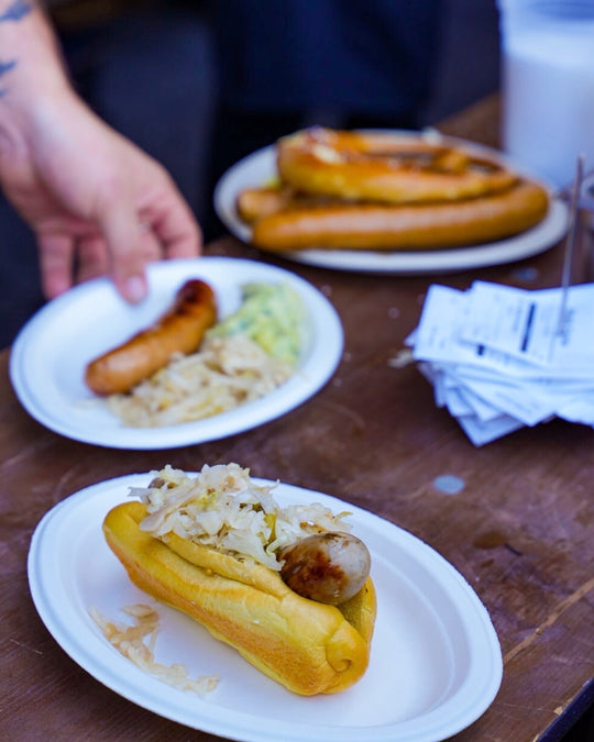 Hot dogs with sauerkraut on paper plates on a wooden table.