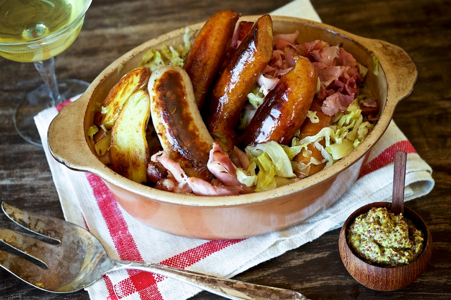 olympia provisions choucroute in a bowl with sliced potatos and cabbage as well as ham.