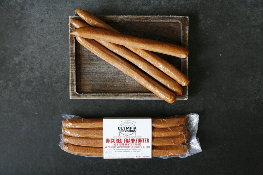 Olympia Provisions Frankfurters both packaged and laid out on a board