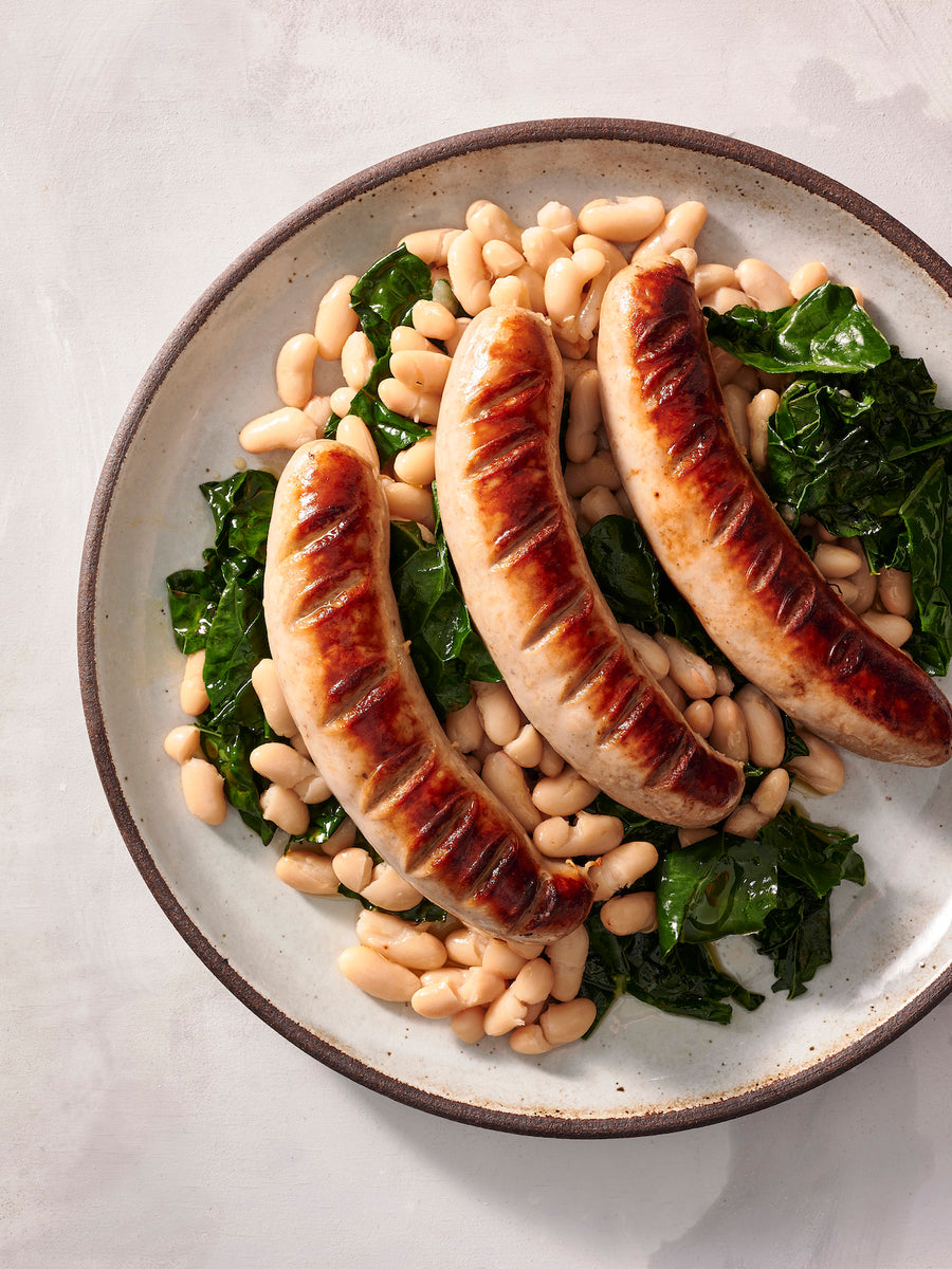 bratwurst on a plate with kale and white beans