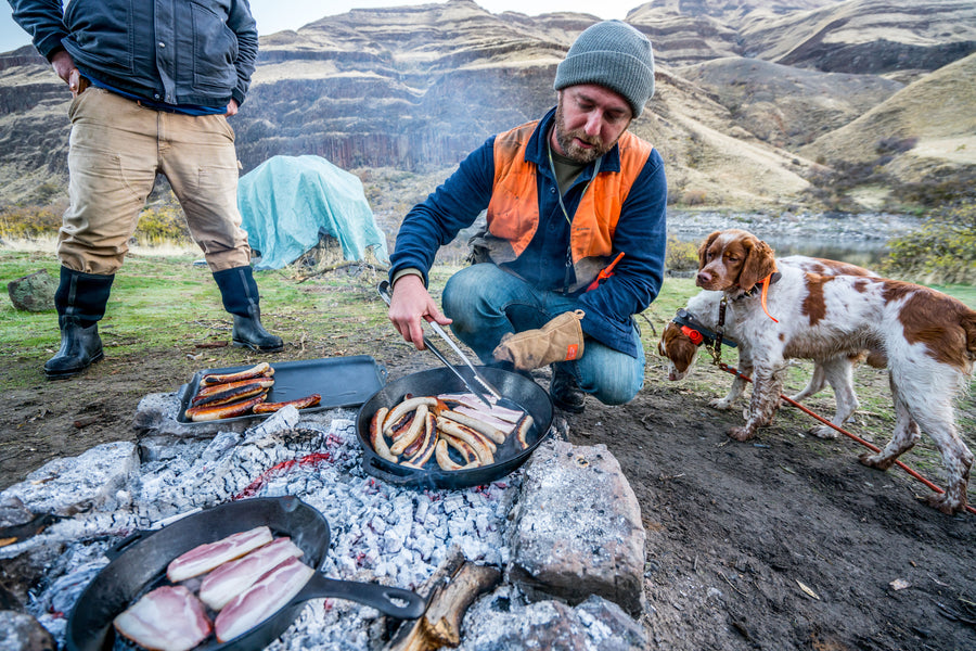 man cooking Olympia Provisions meats on a charcoal fire
