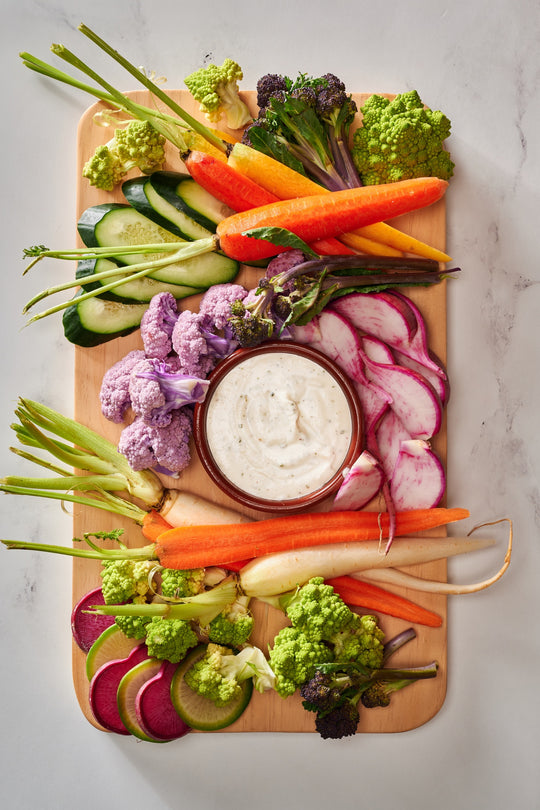 an assortment of vegetables including cucumbers, purple cauliflower, carrots, and parsnips, as well as radishes