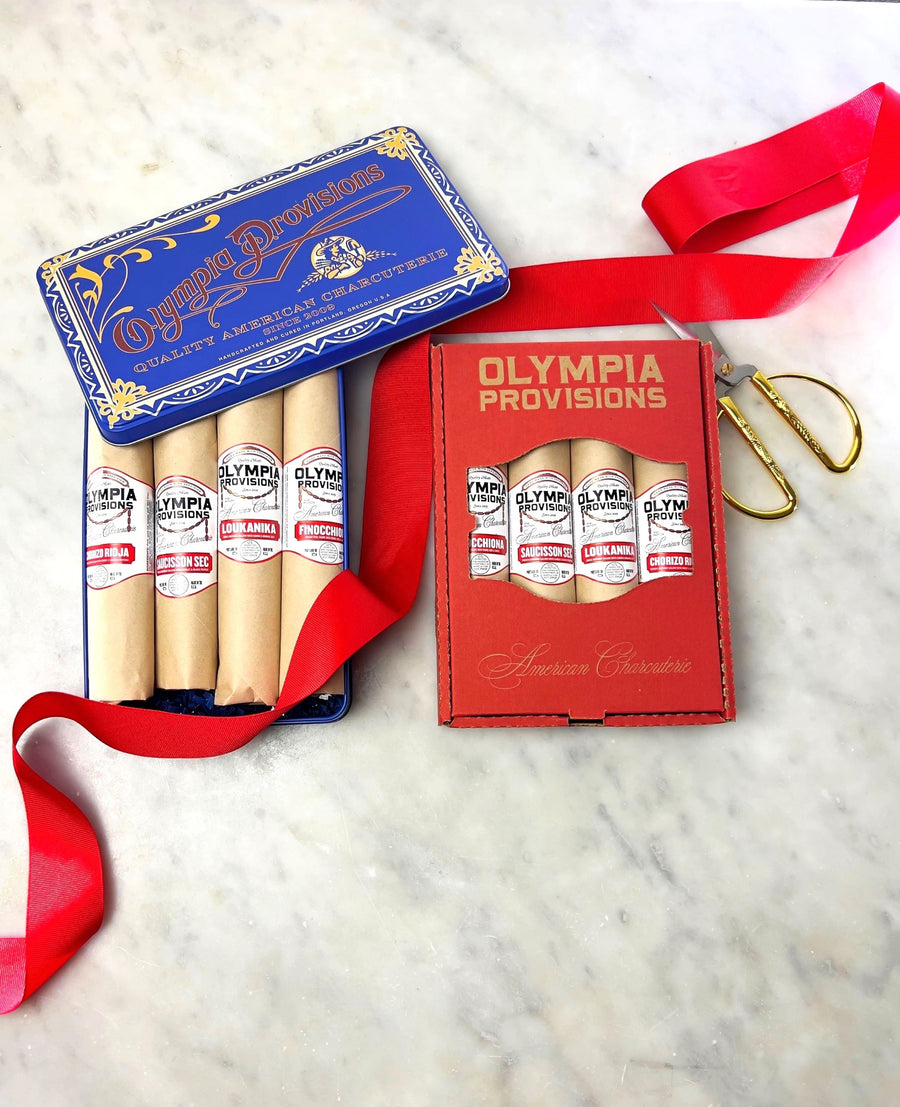 two boxes of olympia provisions salami with a ribbon in the background