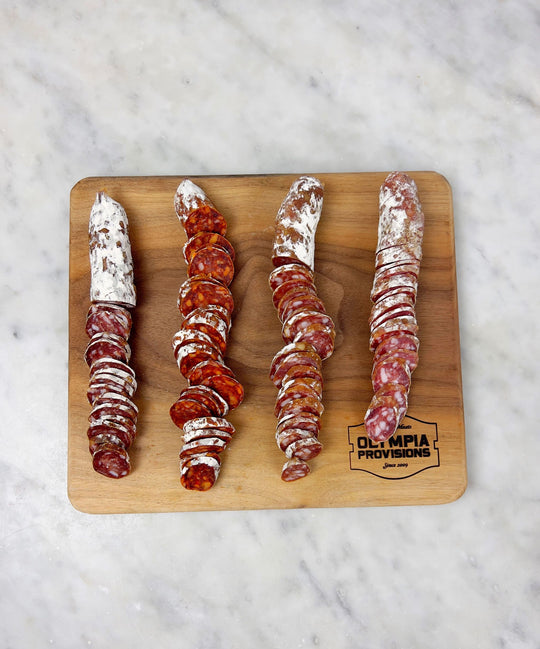 a wooden cutting board with sliced salami