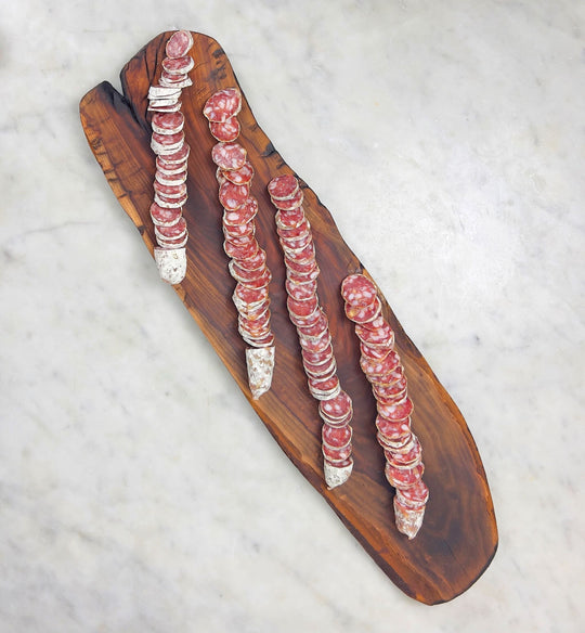 Sliced salami on wood board