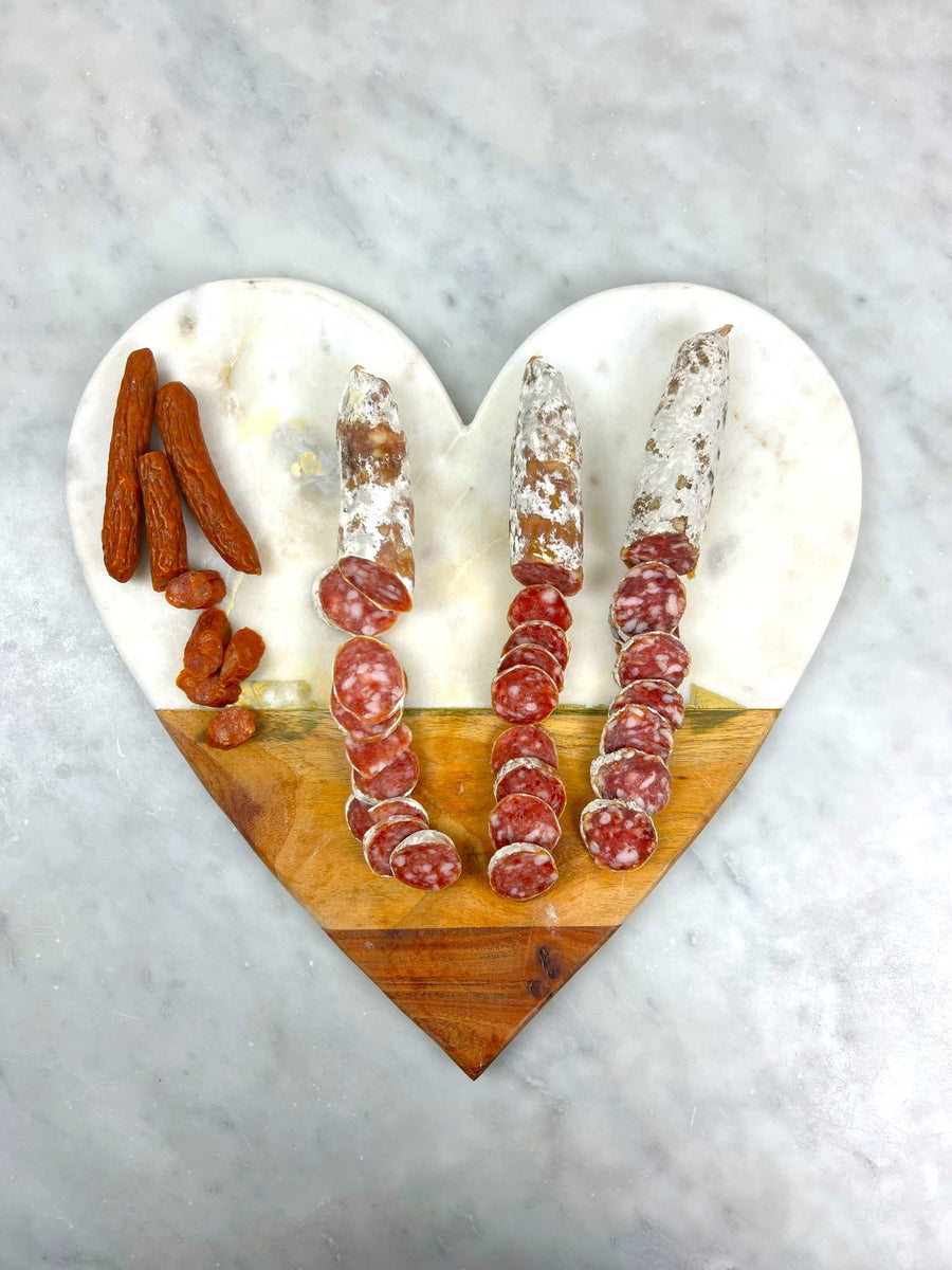 Sliced salami on a heart cutting board