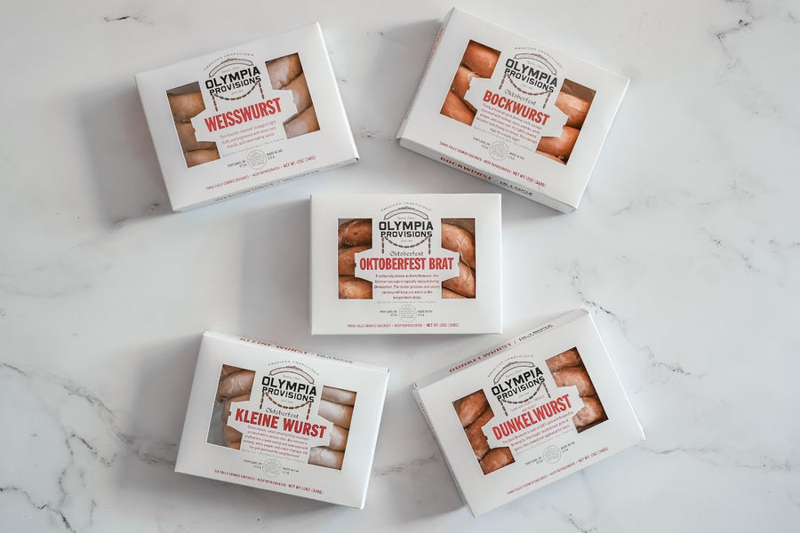 Five boxes of Olympia Oktoberfest Wurst on a marble surface, Bockwurst, Oktoberfest Brat, Dunkelwurst