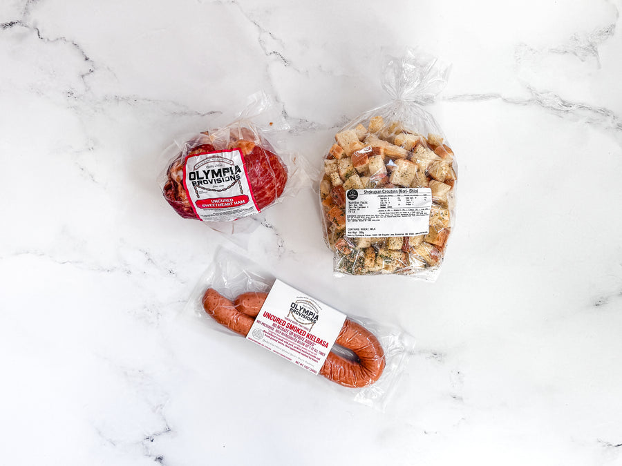 Ham, stuffing, kielbasa of food on a marble surface, featuring visible brand labels.