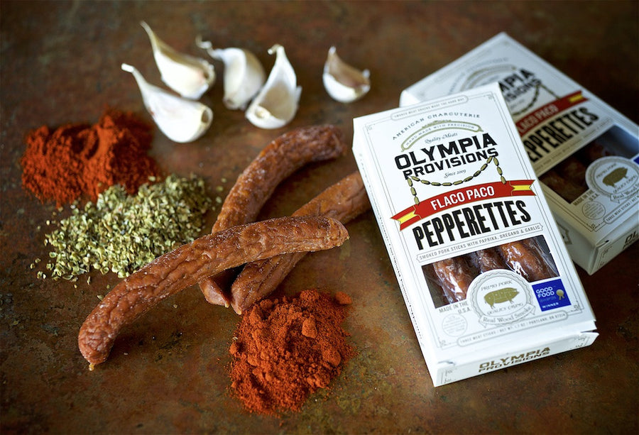 Olympia Provisions Flaco Paco Pepperettes in packages and laid out on a table with spices