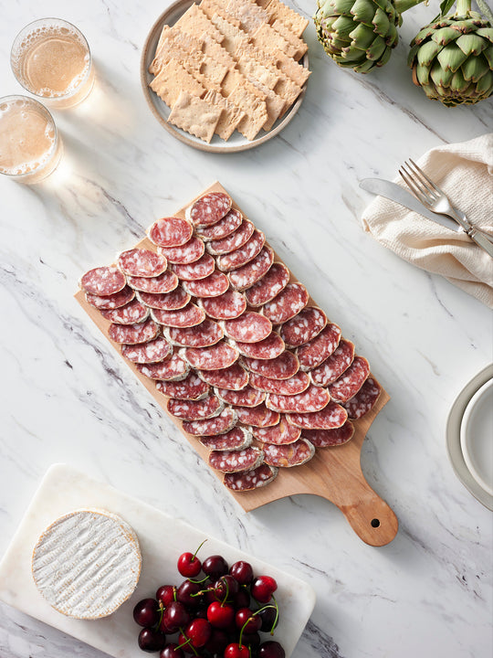 French Salami charcuterie board with cherries, soft cheese, crackers and wine